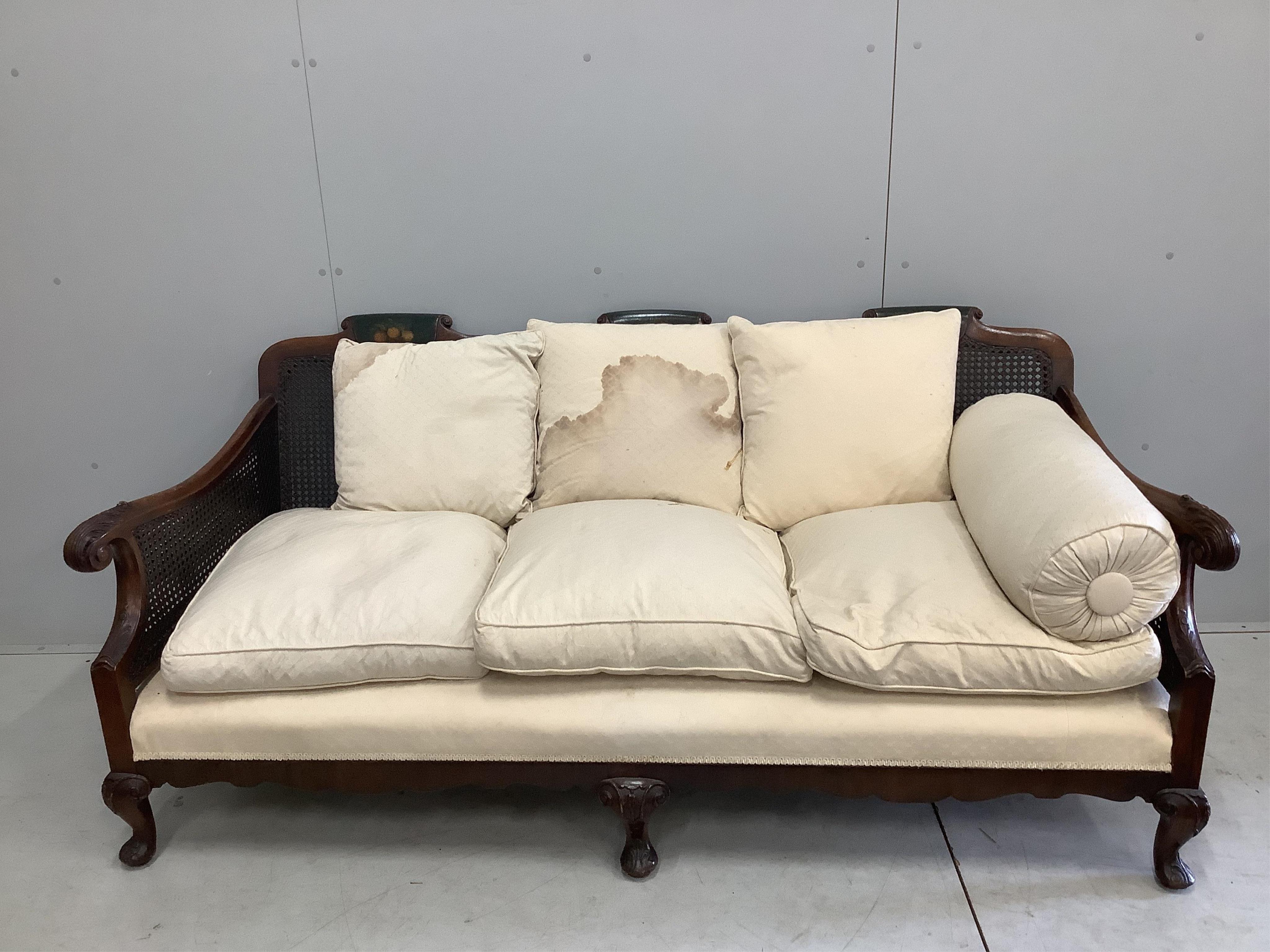 An early 20th century part painted walnut three piece bergere suite, settee width 186cm, depth 78cm, height 80cm. Condition - fair, although one cane panel is damaged and needs repair